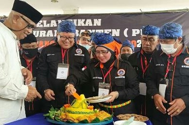Hj. Aida Ratu Pantura Ketua Perkumpulan Urang Banten (PUB) Kabupaten Tangerang saat mempotong nasi tumpeng untuk diberikan secara simbolis kepada ketua umum PUB Drs. H. Taufiequrachman Ruki SH.